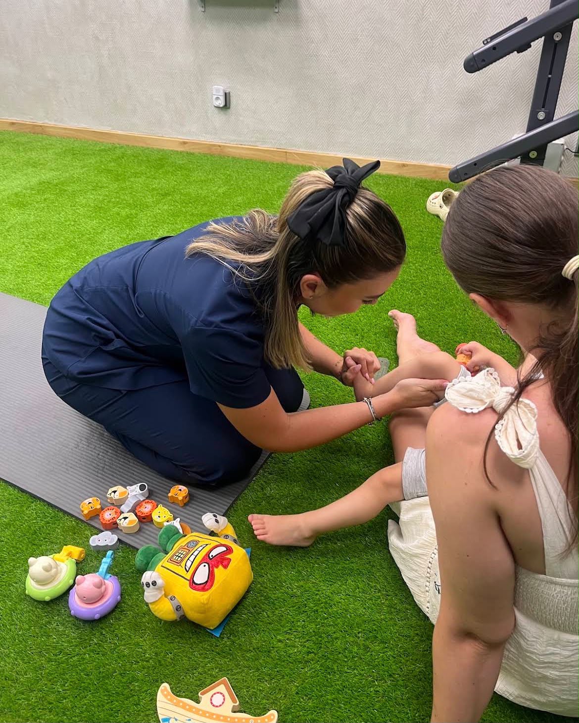 Laura valorando el pie de un peque en consulta, con la madre presente